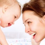 Mama si bebelusul se privesc si isi zambesc